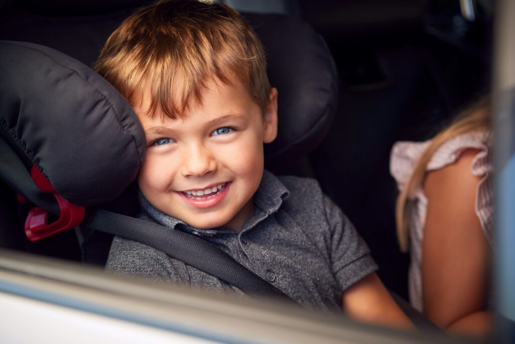 Portrait Of Young Boy Sitting In Child Safety Seat On Car Journey Looking Out Of Window
