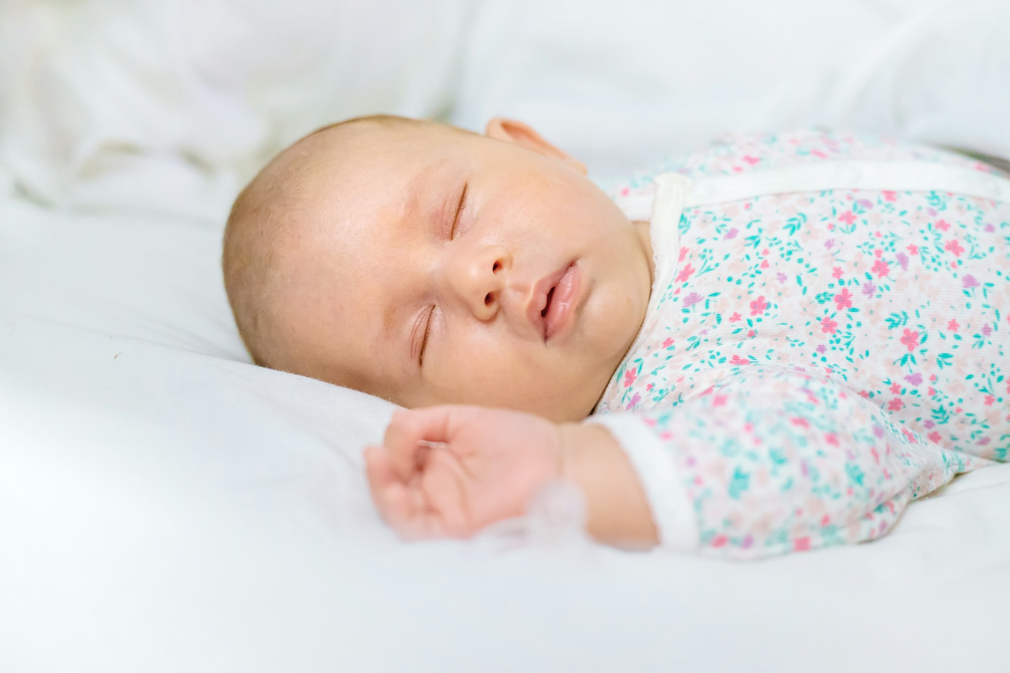 Newborn baby sleeps on a white bed. Selective focus.